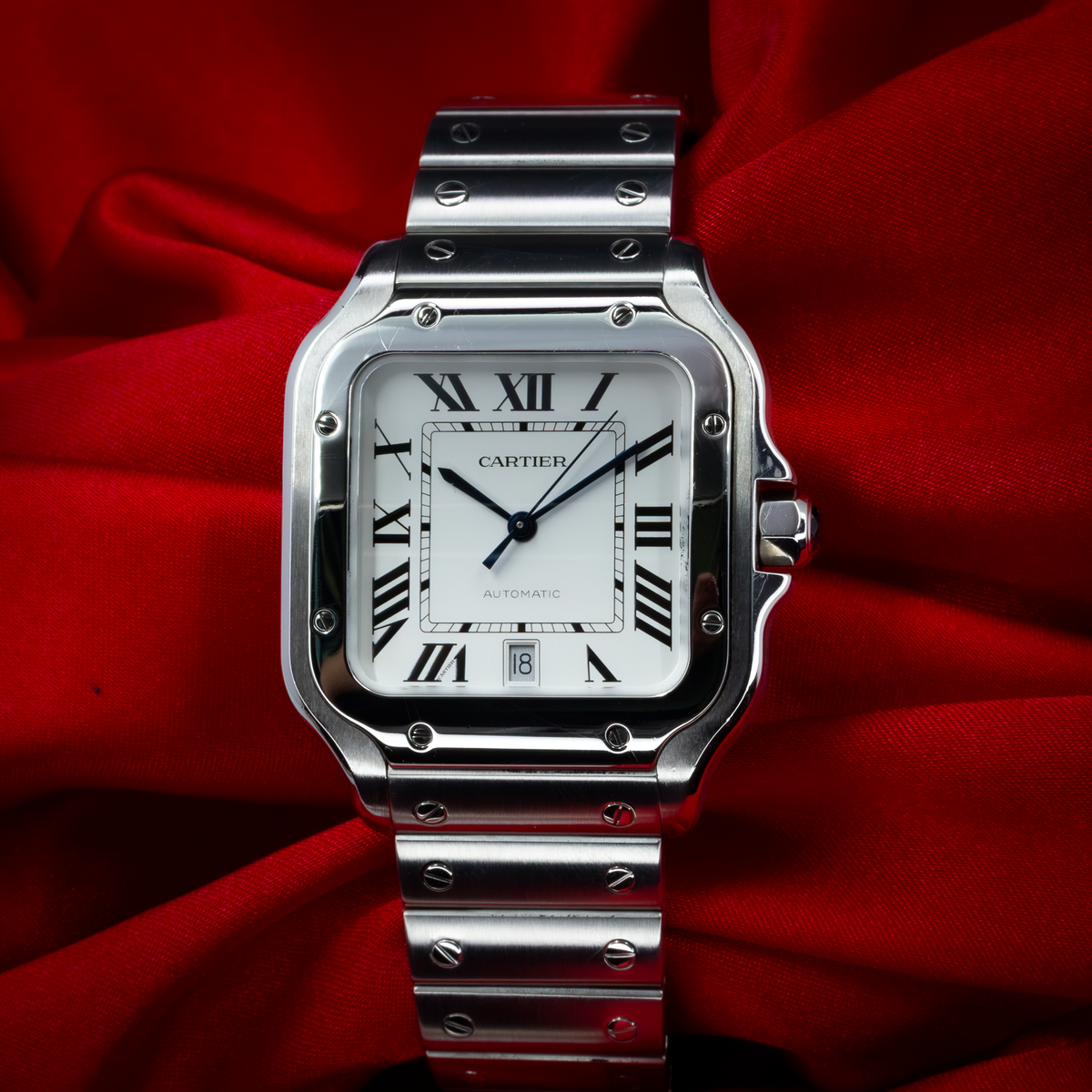 Cartier Santos De Cartier WSSA0018 dial with white face, black Roman numerals, date window, and stainless steel bracelet.
