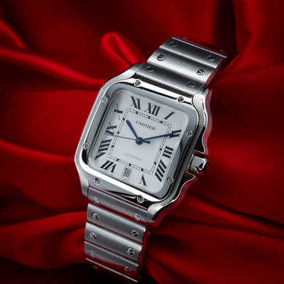 Cartier Santos De Cartier WSSA0018 dial, crown, and bracelet on a red background.