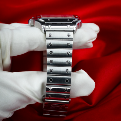 Cartier Santos De Cartier WSSA0018, close-up of the bracelet with exposed screws against red and white fabric.