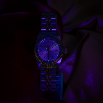 Rolex Oyster Perpetual Lady 67193 dial with glowing luminescent hour markers and hands under UV light.