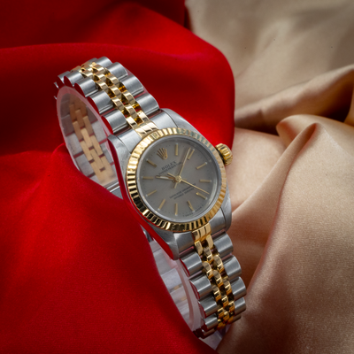 Rolex Oyster Perpetual Lady 67193 dial and bracelet on red and gold fabric.