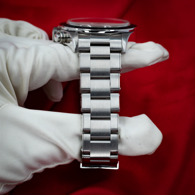 Tudor Black Bay Chrono M79360N-0002 watch held by white-gloved hand, showing case side and steel bracelet.