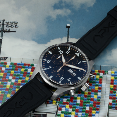 IWC Pilot’s Watch Chronograph APXGP iw378009, full dial view with black rubber strap on racetrack background.