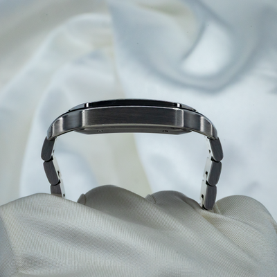 Cartier Santos WSSA0063 side profile with brushed steel case and bracelet on white fabric.