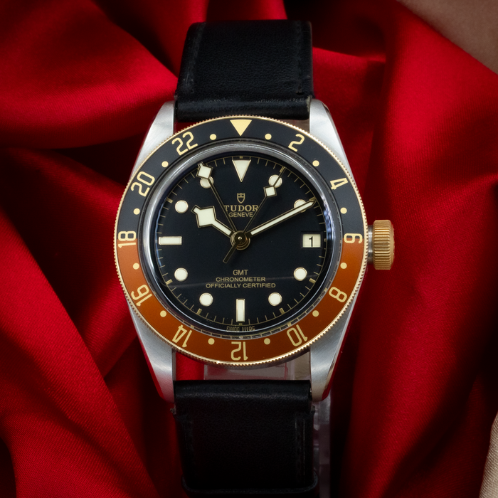 Tudor Black Bay Gmt S&g M79833MN-0003, close up of the black dial and brown/black 24-hour bezel with a black leather strap.