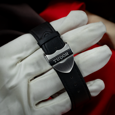 Tudor Black Bay Gmt S&g M79833MN-0003 clasp, showing the branded shield-shaped buckle on a black leather strap.