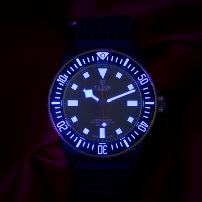 Tudor Alinghi Red Bull Pelagos Fxd – Racing M25707KN dial, glowing blue luminescent hands and hour markers in dark.