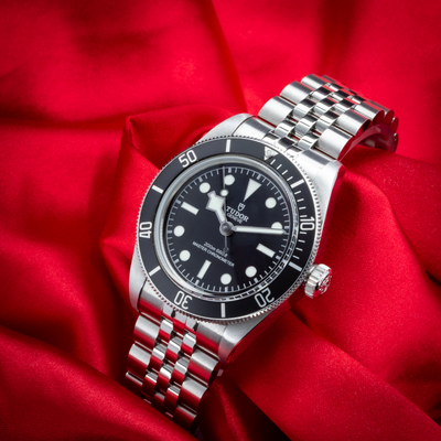Tudor Black Bay 41mm M7941A1A0NU-0003, full watch view with a black dial and steel bracelet on red fabric.