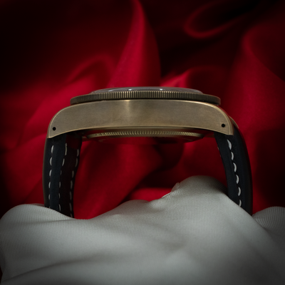 Tudor Black Bay M79250BA-0001 side profile view showing the bronze case and black leather strap with white stitching.