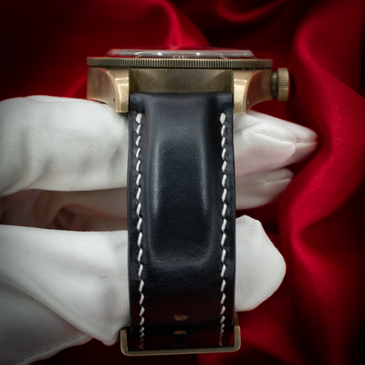 Tudor Black Bay M79250BA-0001 side profile with crown, black strap, and buckle on white glove.
