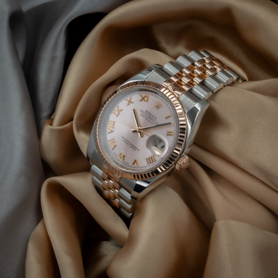Rolex Datejust 36 reference 116231 dial, rose gold fluted bezel, Jubilee bracelet and crown on beige fabric.