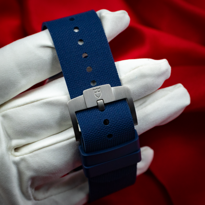 Tudor Pelagos FXD Marine Nationale 25707B/23-0001 clasp on blue textile strap, held by a gloved hand.