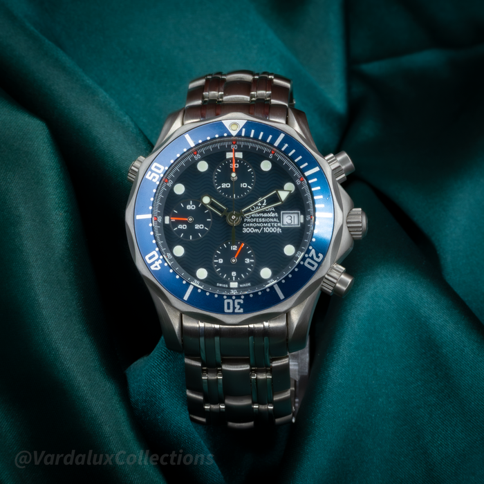 Omega Seamaster 2298.80.00 watch, with a blue wave dial, stainless steel bracelet and blue bezel, lying on green fabric.