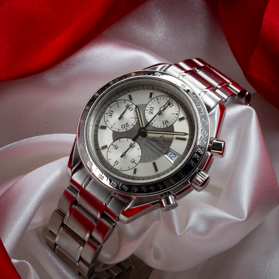 Omega Speedmaster Date 3513.30.00 watch, full dial view with stainless steel bracelet on red and white fabric.