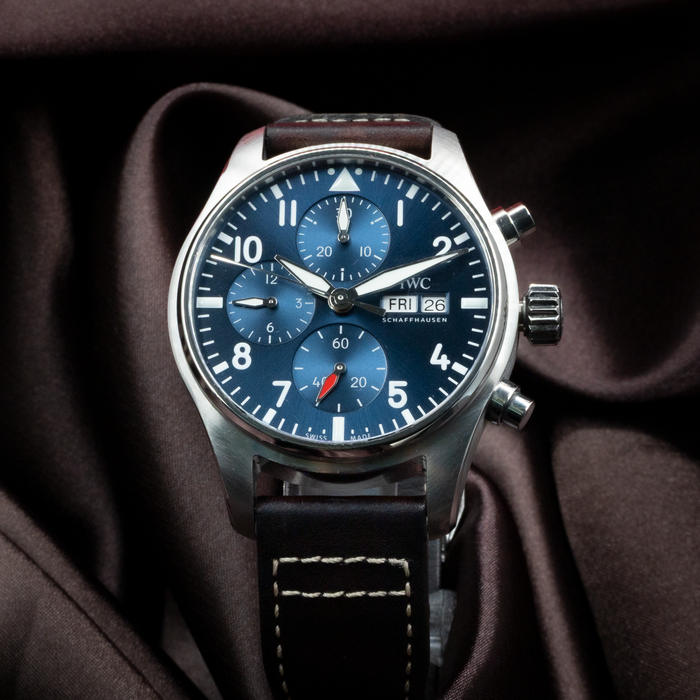 IWC Pilot Chronograph IW388101 dial, day-date window, and sub-dials on a blue face with a brown leather strap.