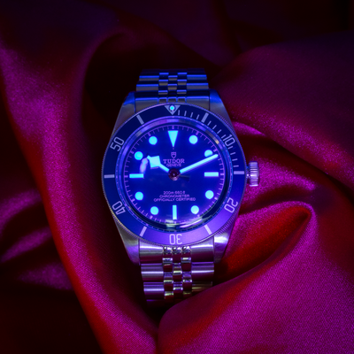 Tudor Black Bay Fifty-Eight Blue M79030B-0001, dial with bright blue luminescence and steel bracelet on fabric.