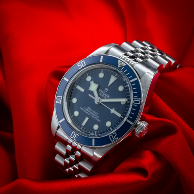 Tudor Black Bay Fifty-Eight Blue M79030B-0001, full dial, bezel, and crown visible, on a red fabric.