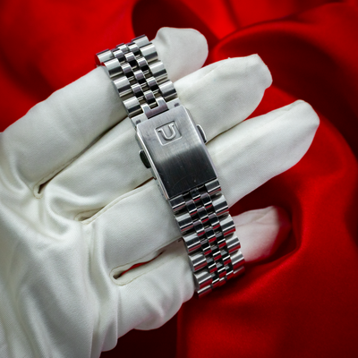 Tudor Black Bay Fifty-Eight Blue M79030B-0001 bracelet and clasp with logo, held by a white gloved hand.