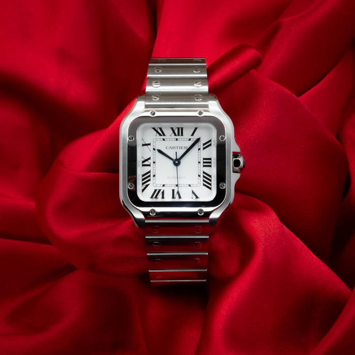 Cartier Santos De Cartier WSSA0029, a stainless steel watch with a white dial and black Roman numerals on red silk.