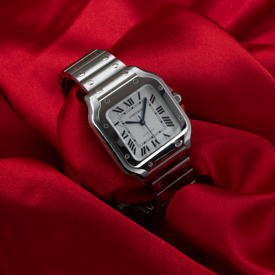 Cartier Santos De Cartier WSSA0029 dial and bracelet on a red background.