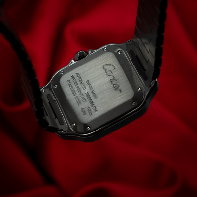 Cartier Santos De Cartier WSSA0029 watch with an engraved stainless steel caseback on a red background.