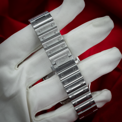 Cartier Santos De Cartier White Dial WSSA0029, brushed steel bracelet and clasp with Cartier logo, held by a gloved hand.
