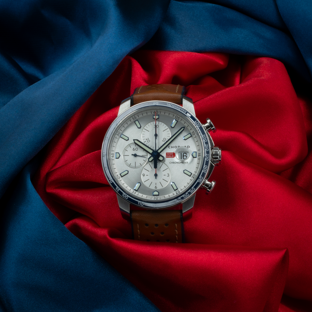 Chopard Mille Miglia Gts Race Edition 2022 168571-3010 dial close-up with a brown leather strap on red and blue fabric.