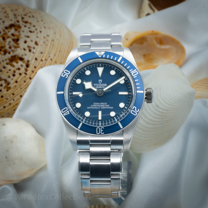 Tudor Black Bay 58 79030B, watch with blue dial and bezel on a metal bracelet, surrounded by seashells.