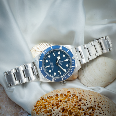 Tudor Black Bay 58 79030B, full watch with blue dial and bezel on a bracelet against a white silk backdrop.