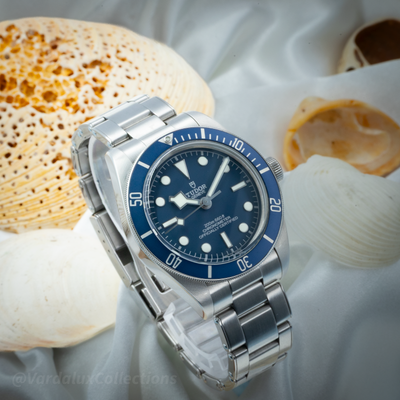 Tudor Black Bay 58 79030B full face view with blue bezel, dial, and metal bracelet on a white silk surface.