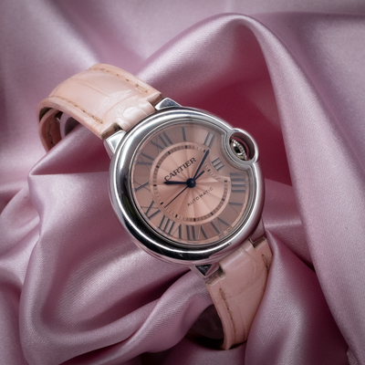 Cartier ballon bleu wsbb0002 watch dial, light pink strap, and crown, on pink satin.