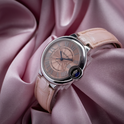 Cartier ballon bleu wsbb0002 watch dial, pink crocodile leather strap, and blue cabochon winding crown on pink satin.