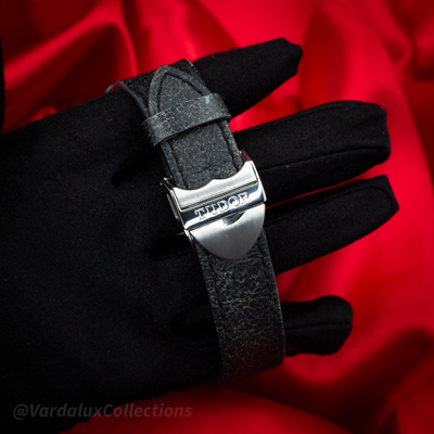Tudor Black Bay 79730-0005. Black leather strap with Tudor branded buckle on a gloved hand.
