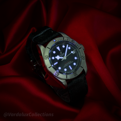 Tudor Black Bay 79730-0005, luminous dial glowing on a dark red satin background.