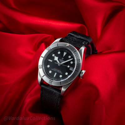 Tudor Black Bay 79730-0005, showing the watch on a red fabric background with a close-up of the dial and leather strap.
