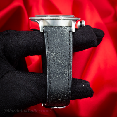 Tudor Black Bay 79730-0005, side view of the case, crown, and black leather strap with buckle held by a gloved hand.