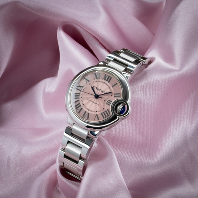 Cartier Ballon Bleu W6920100 watch with pink dial and stainless steel bracelet on pink satin.