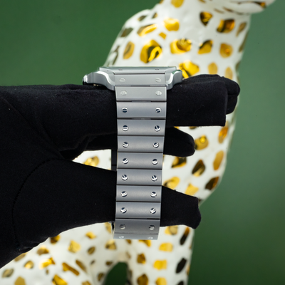 Cartier Santos WSSA0089, side view of the watch and metal bracelet with visible screws, held by a gloved hand.