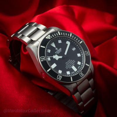 Tudor Pelagos 25600TN dial with date window, black bezel, titanium bracelet, and crown on red satin.