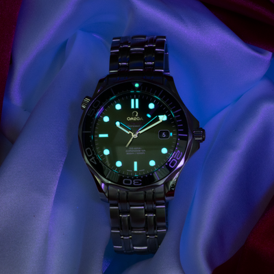 Omega Seamaster Diver 212.30.41.20.01.003 dial, glowing green lume on markers, hands, and bezel numbers.