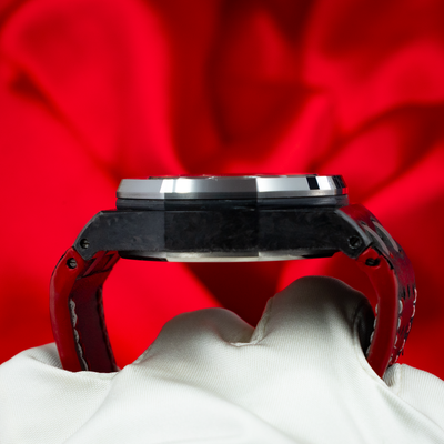 Audemars Piguet Jarno Trulli 26202AU.OO.D002CA.01, side case and strap detail, with white glove and red background.