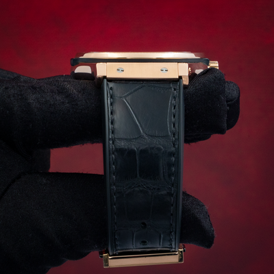 Hublot Gold Skeleton 505.OX.0180.LR, side view of rose gold case and black alligator strap held by gloved hand.